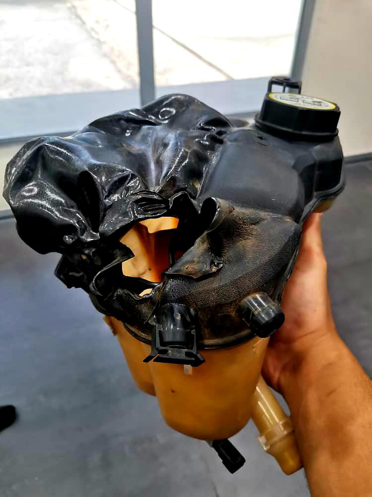 Gambar ini menunjukkan expansion tank dari sebuah Range Rover Evoque yang telah rosak teruk dan meletup. Tujuan utama gambar ini adalah untuk menunjukkan kesan kerosakan sistem penyejukan kenderaan apabila terdapat masalah seperti overheating atau kegagalan komponen kritikal seperti thermostat, radiator, atau kipas penyejuk. Ia juga berfungsi sebagai amaran visual kepada pemilik kenderaan untuk lebih berhati-hati dan melakukan penyelenggaraan berkala bagi mengelakkan kerosakan serius seperti ini.